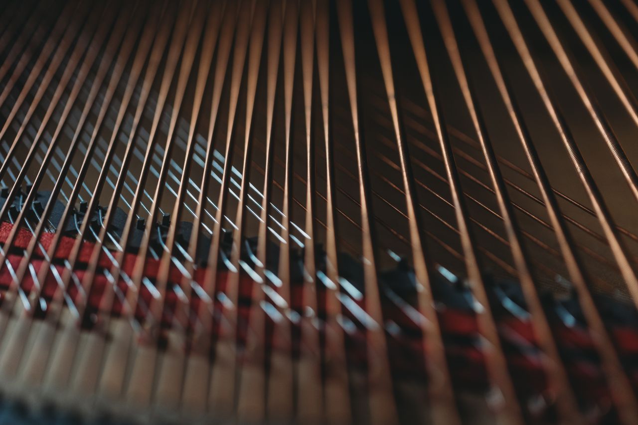 Artistic close-up shot of piano strings, showcasing their design in warm lighting.